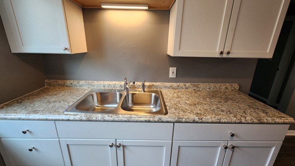 a kitchen with white cabinets and granite counter tops and a sink