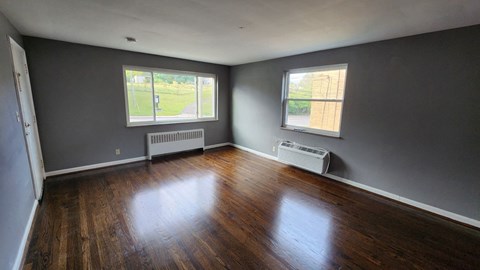 the living room of a house with wooden floors and grey walls