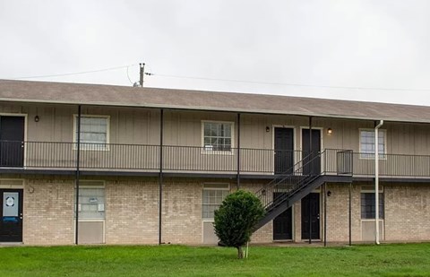 A building with a balcony and a tree in front of it.