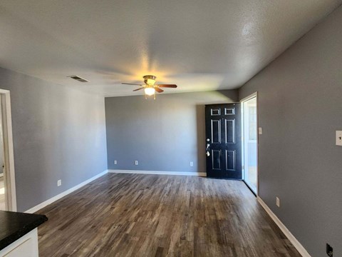 A room with a ceiling fan and wooden flooring.