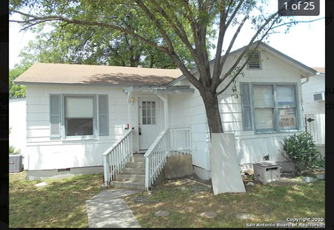 a small white house with a tree in front of it