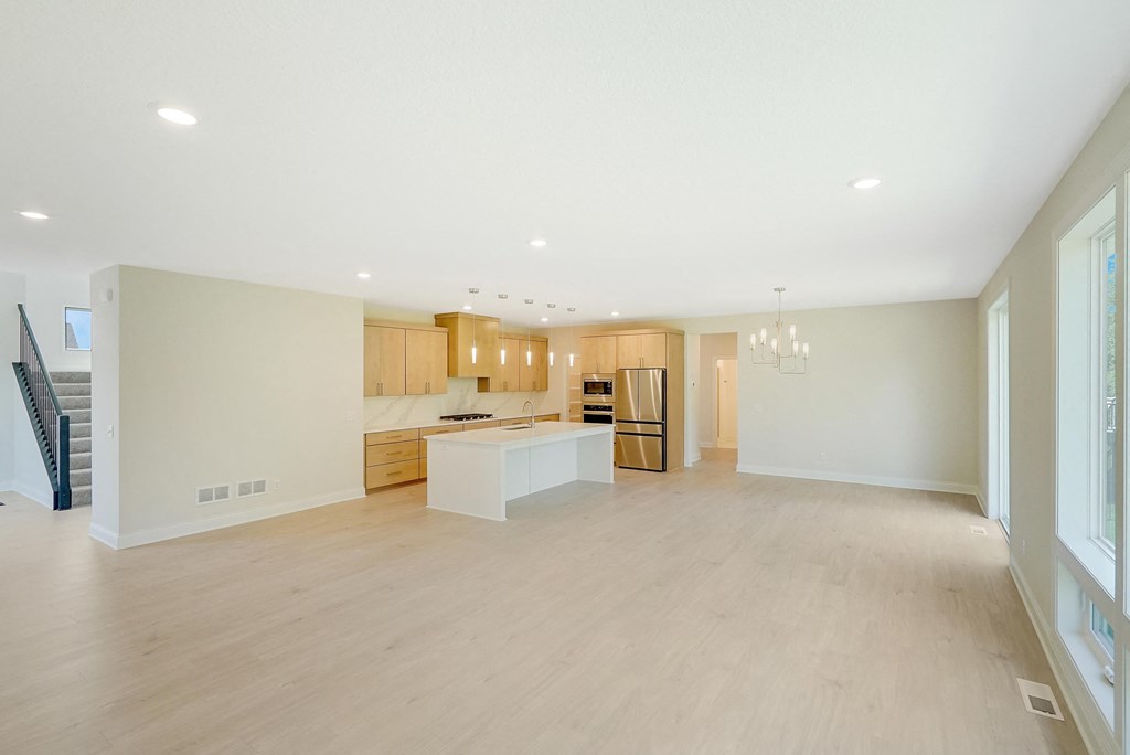 the living room and kitchen of a new home with white walls and wood floors