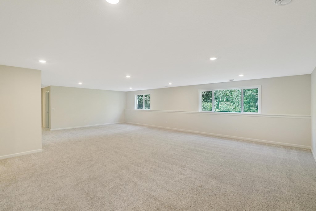 a spacious living room with white walls and a window