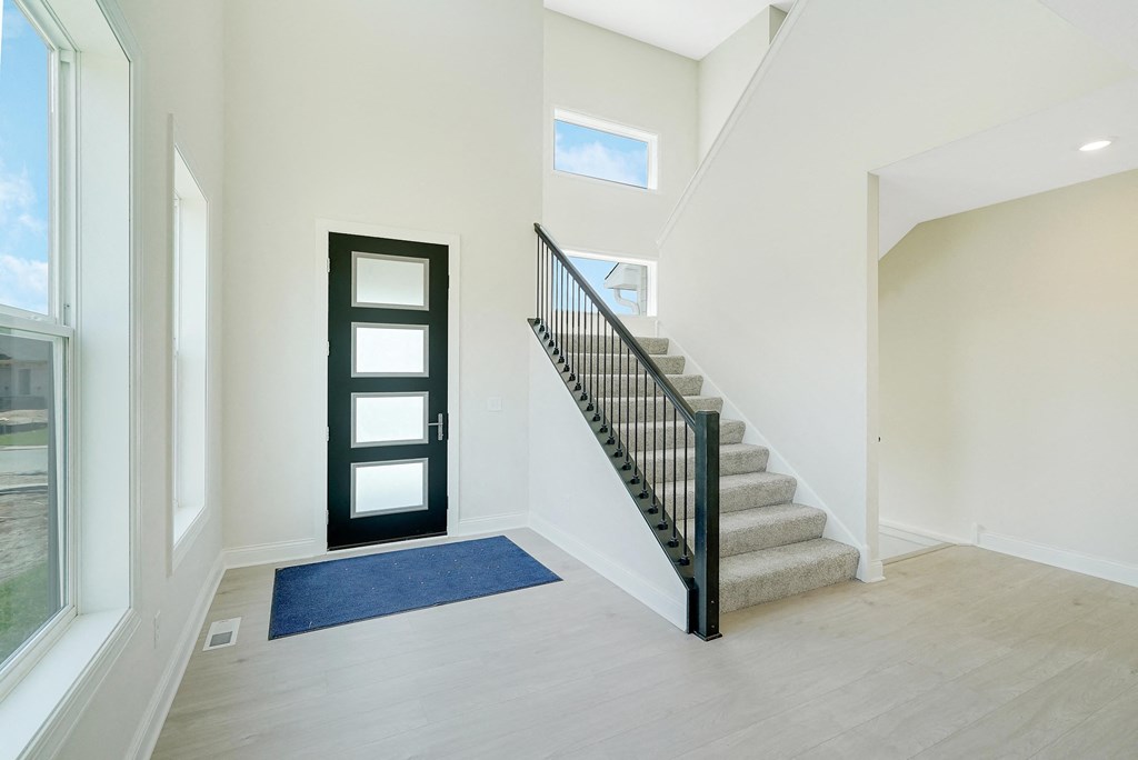 the entryway of a house with stairs and a door to a stairwell