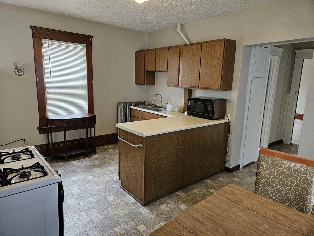 an empty kitchen with a stove and a microwave