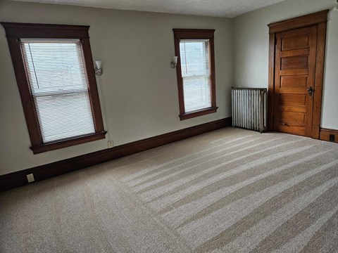 a large empty room with a wooden door and two windows