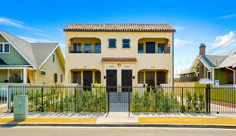 A yellow house with a black gate in front.