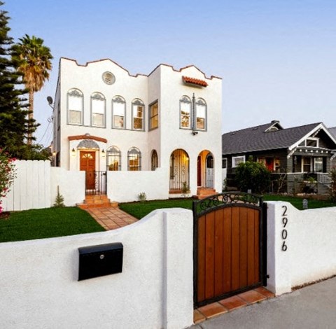 A white house with a black mailbox and a wooden gate.