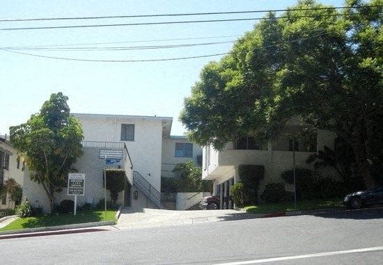 a white apartment building with trees in front of it