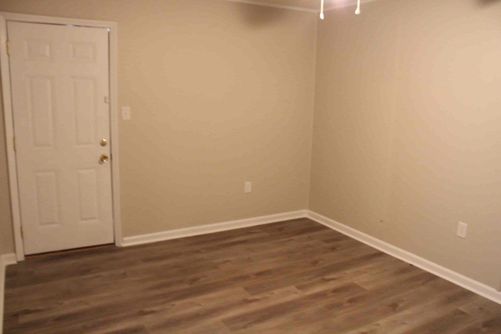 an empty room with wooden floors and a white door