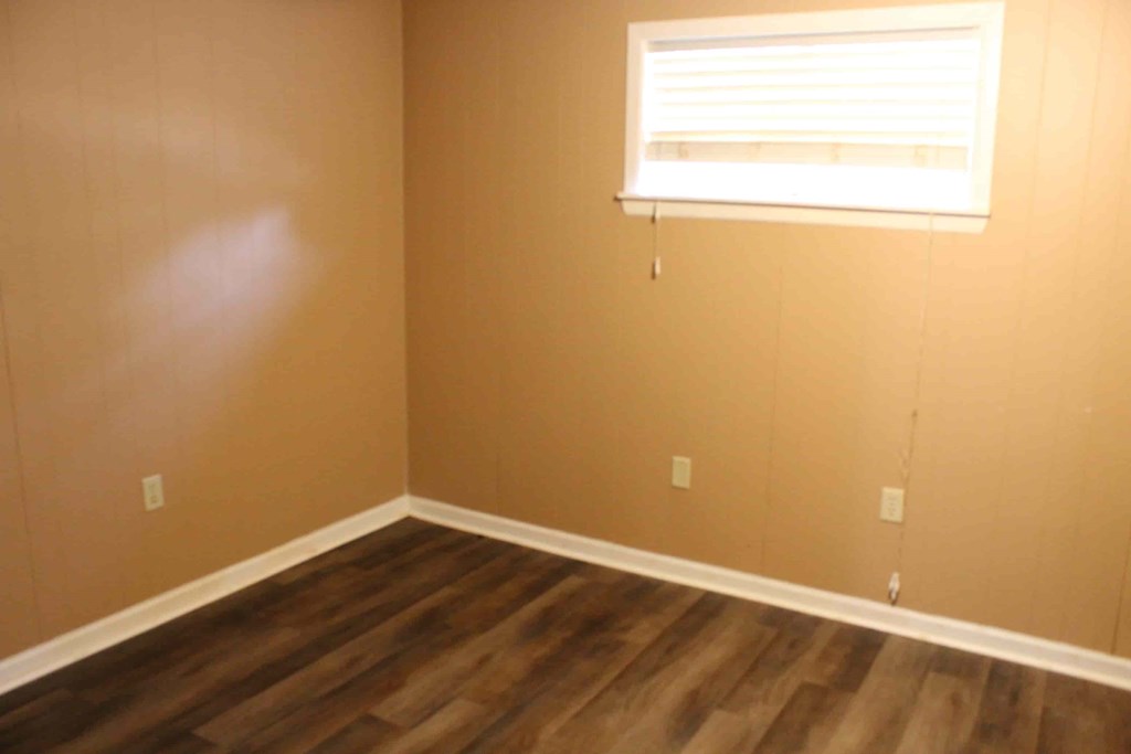 an empty room with a window and wooden floors