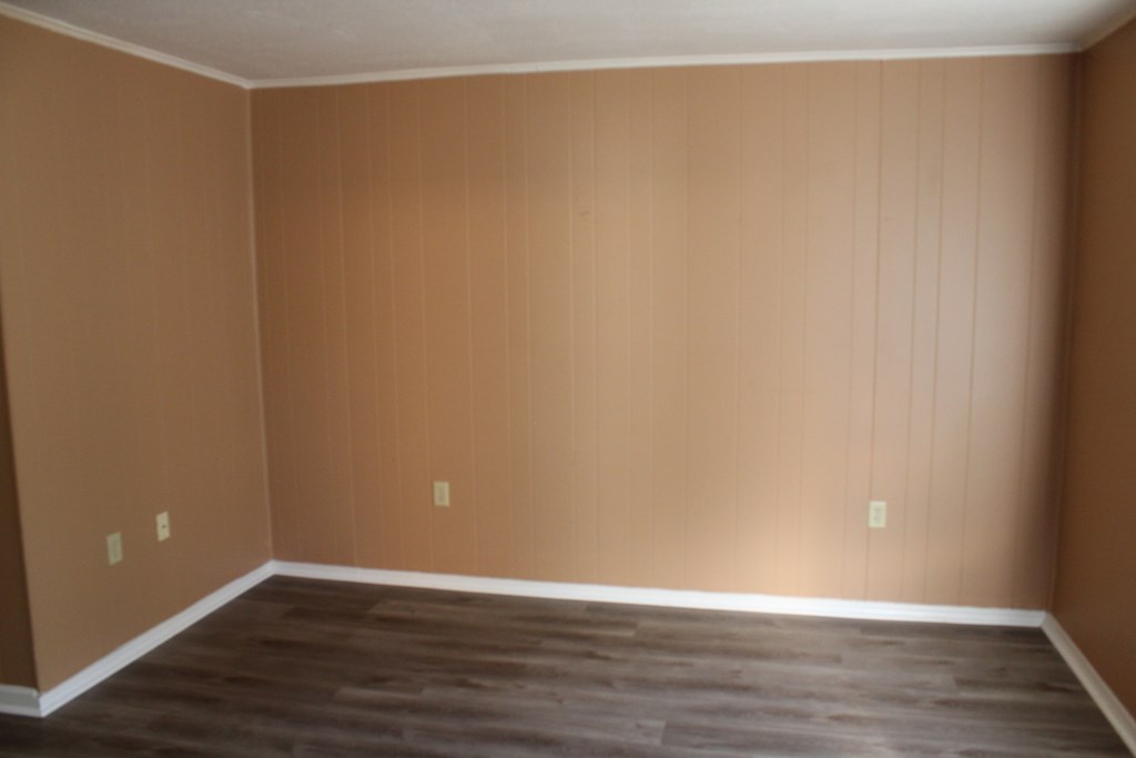 an empty living room with brown walls and a wooden floor