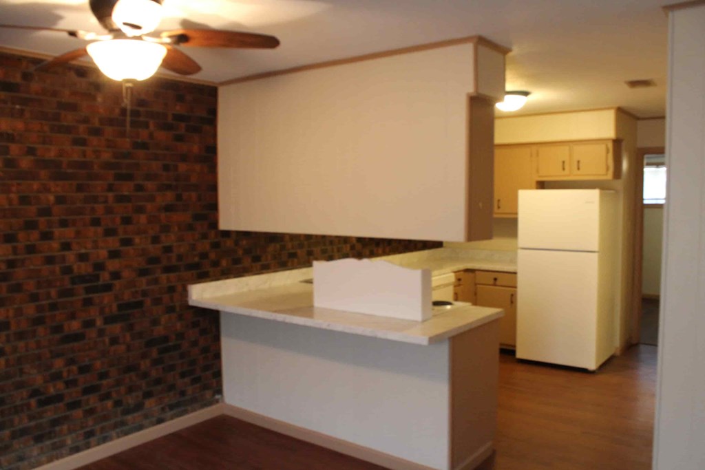 an empty kitchen with a counter top and a refrigerator