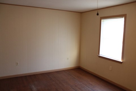 an empty living room with wood floors and a window