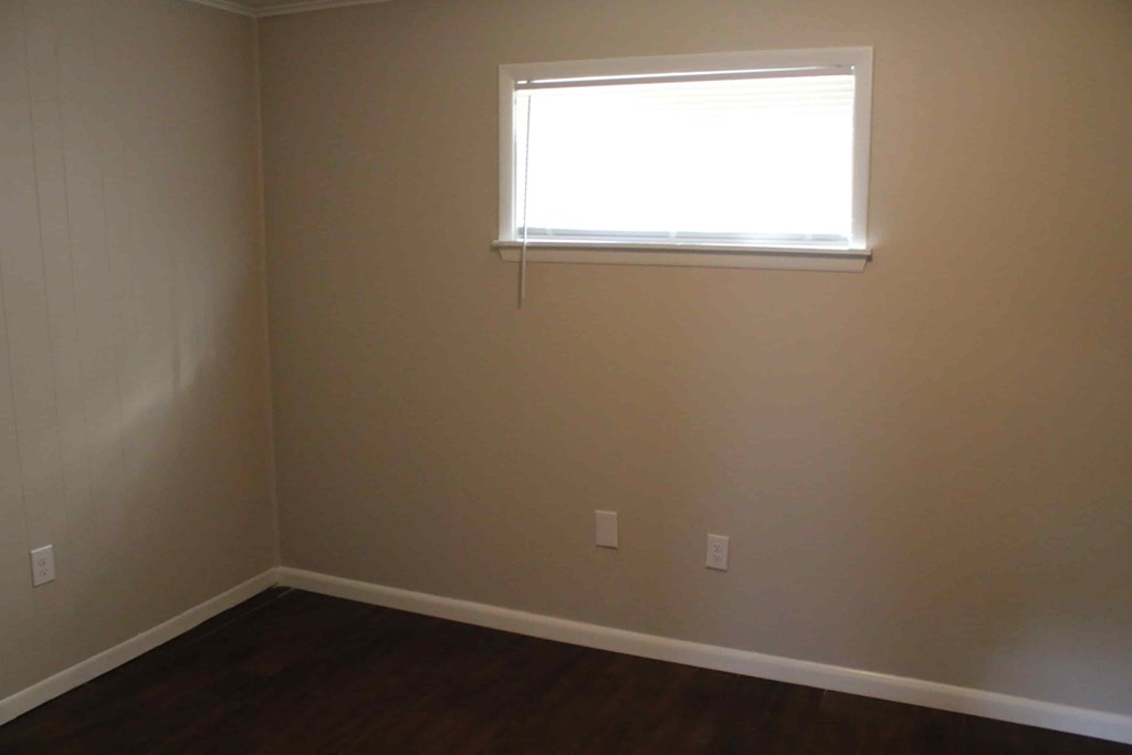 an empty room with a window and a wooden floor