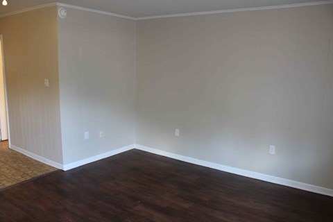 an empty living room with wooden floors and white walls