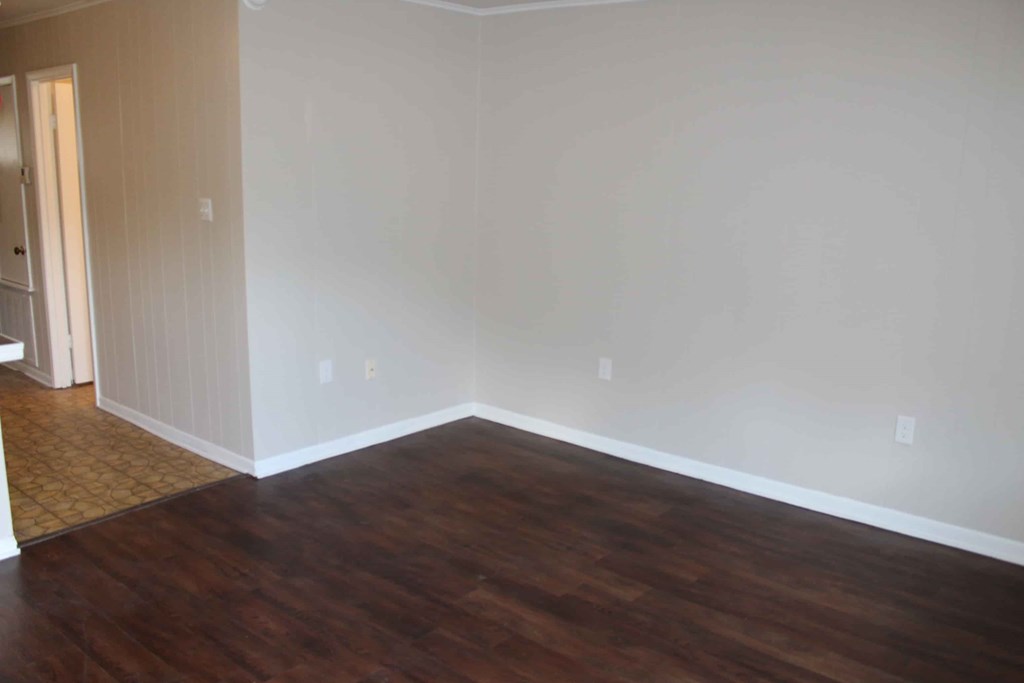 an empty living room with wooden floors and white walls