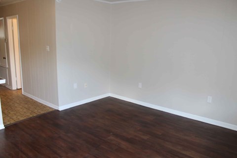 an empty living room with wooden floors and white walls