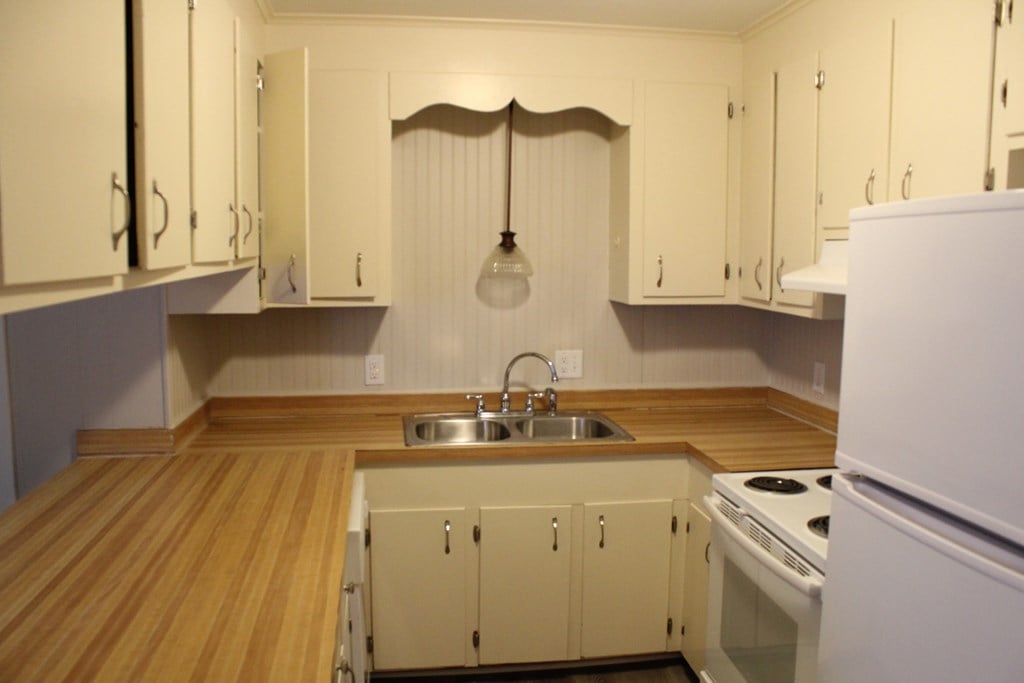 a kitchen with white cabinets and a sink and a refrigerator