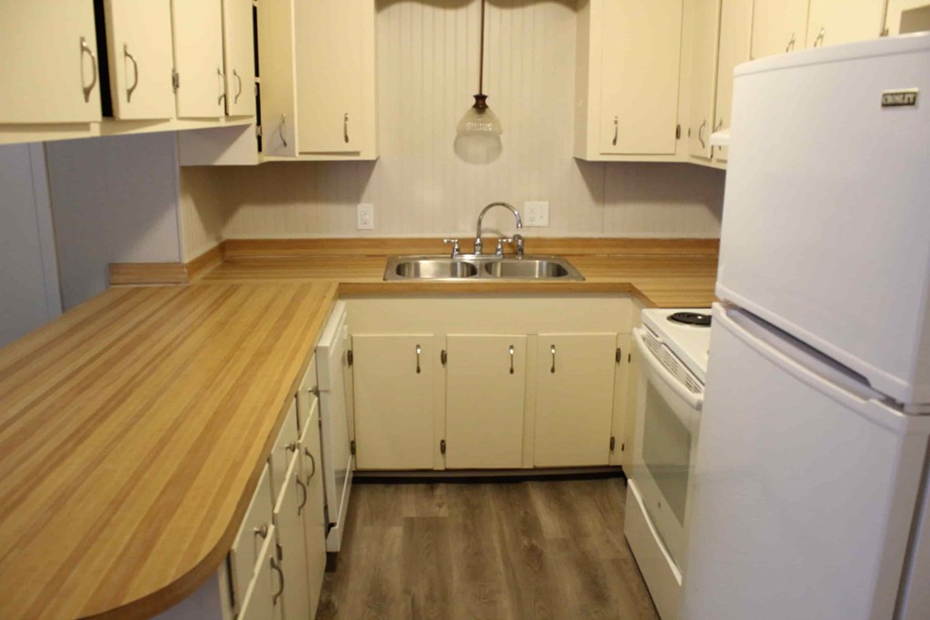 a kitchen with white cabinets and a wooden counter top