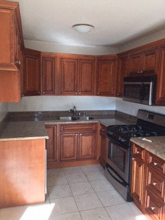 an empty kitchen with wooden cabinets and black appliances