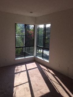 an empty living room with windows and a balcony