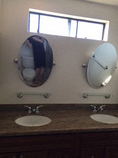 two mirrors on the wall above three sinks in a bathroom