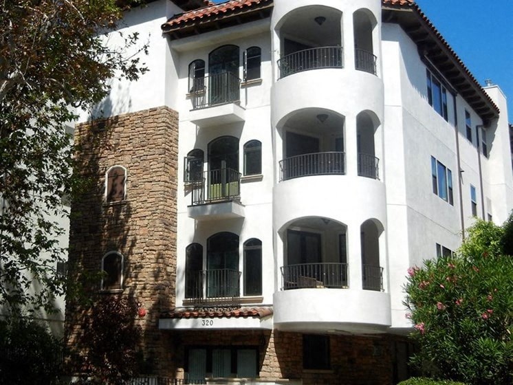 a white building with balconies and a tree