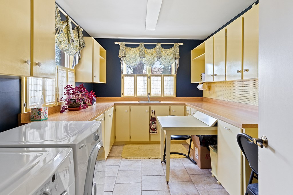 a kitchen with yellow cabinets and a table and a washing machine