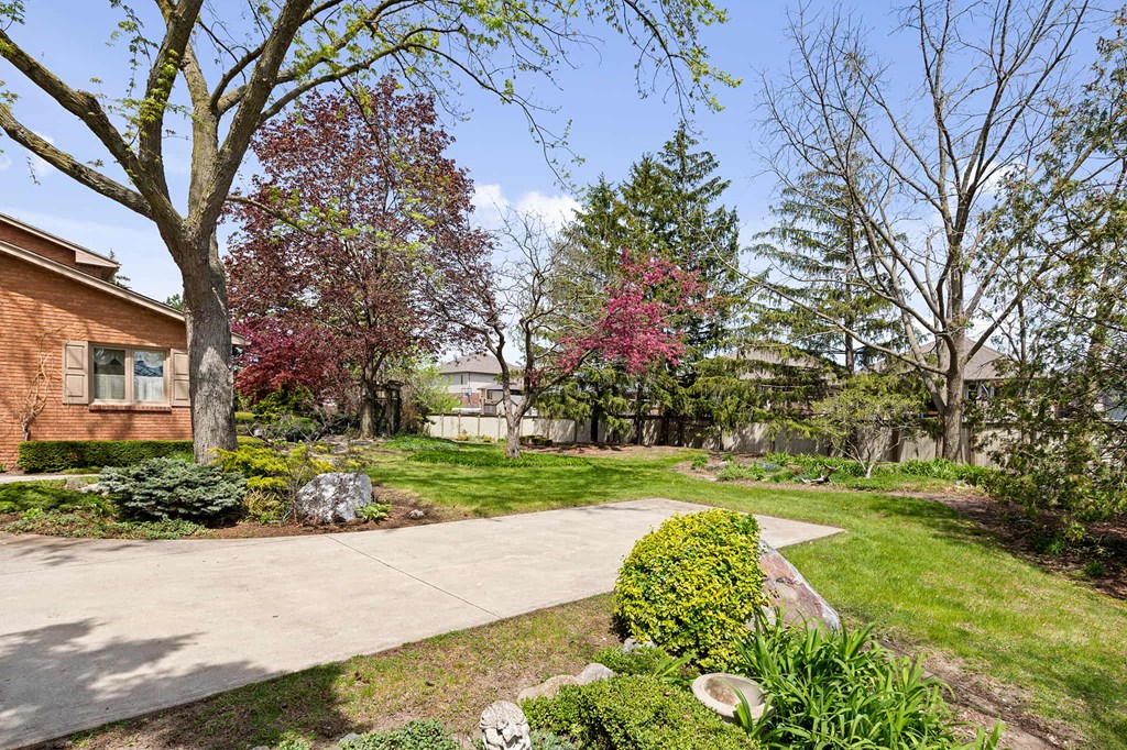 a sidewalk leading to a house with a yard and trees