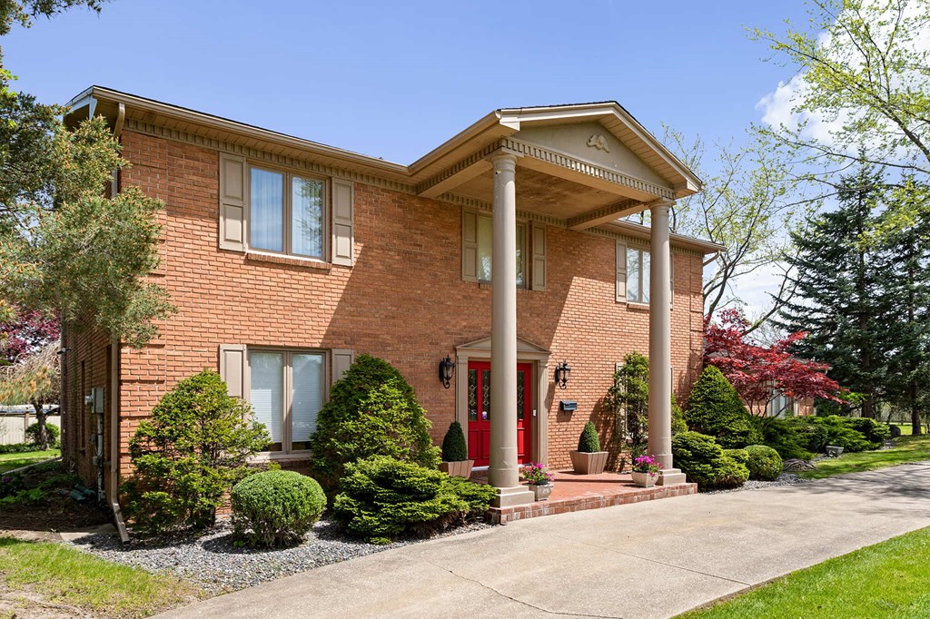the front of a brick house with columns and a driveway