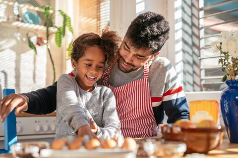 a father and daughter preparing food in the kitchen