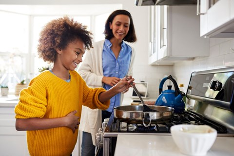 a mother and daughter cooking in a kitchen with a stove