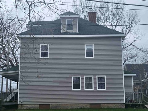 the side of a house with four windows and a roof