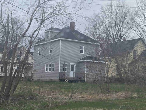a gray house with a black roof and some trees