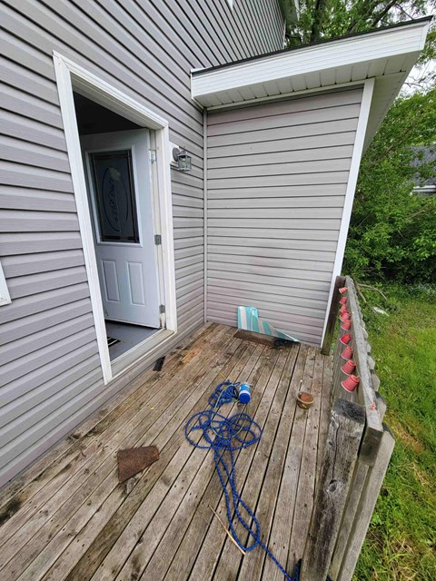 the back deck of a house with a blue rope on the ground