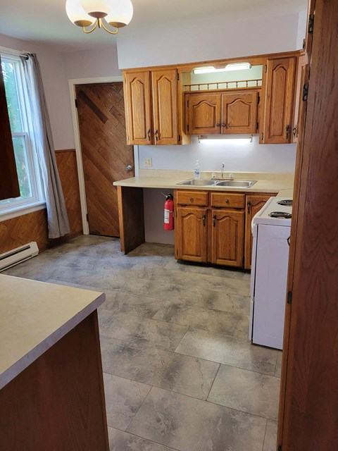 an empty kitchen with wooden cabinets and a stove