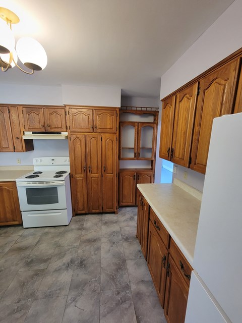 a kitchen with wooden cabinets and a white stove and refrigerator