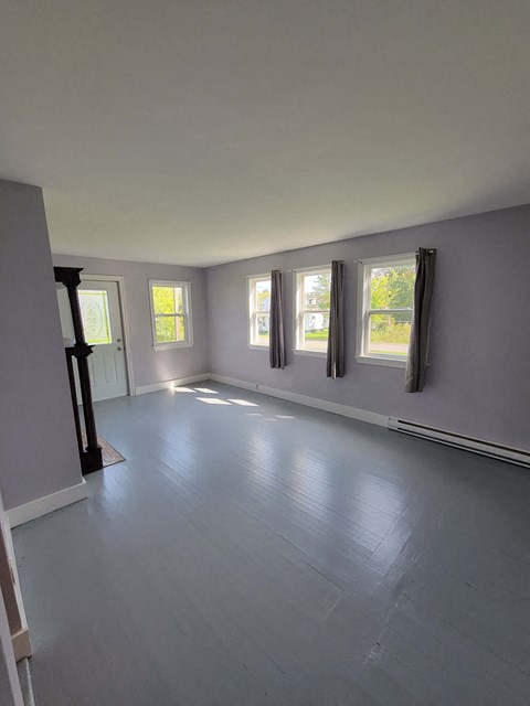 an empty living room with grey walls and windows