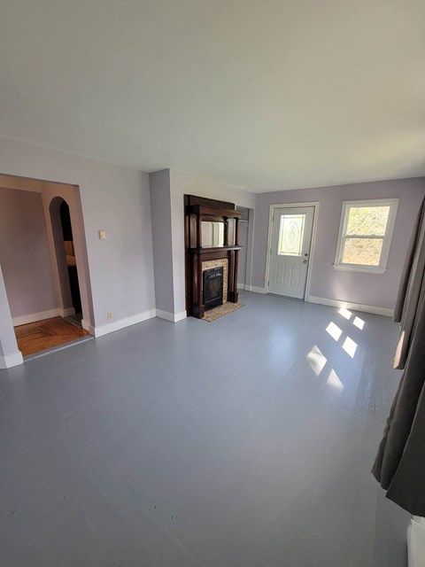 an empty living room with white walls and a fireplace