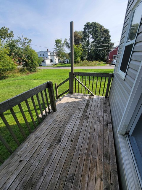 a deck with a view of a yard and a house