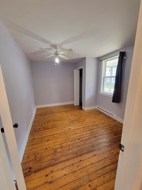 a living room with wood floors and a ceiling fan