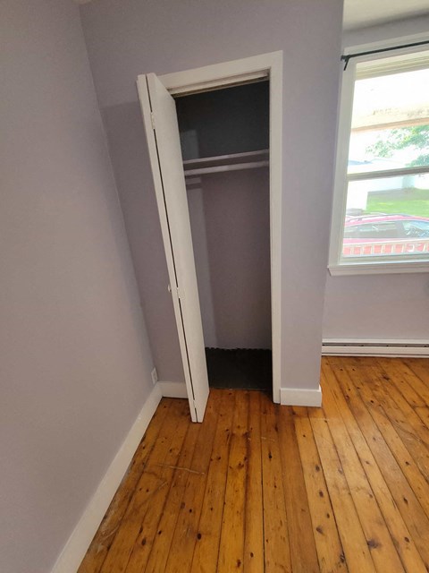 an open closet door in a room with wooden floors
