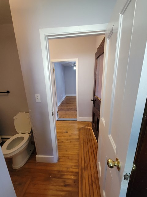 a small bathroom with a toilet and a hallway with a door open