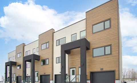 a row of modern apartment buildings with wood and black doors
