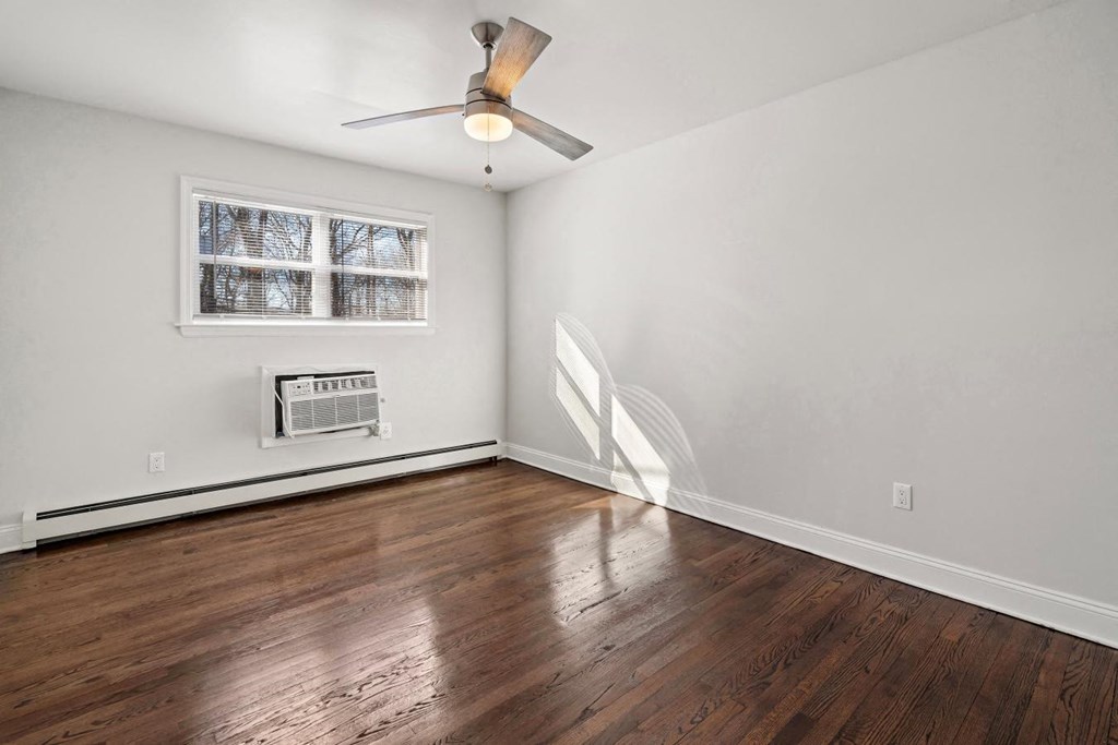 an empty living room with wood floors and a ceiling fan