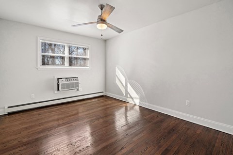 an empty living room with wood floors and a ceiling fan