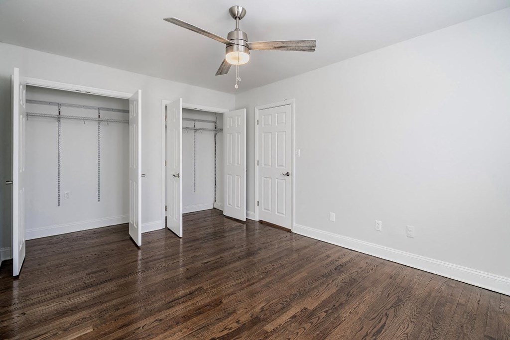 an empty living room with wood floors and a ceiling fan