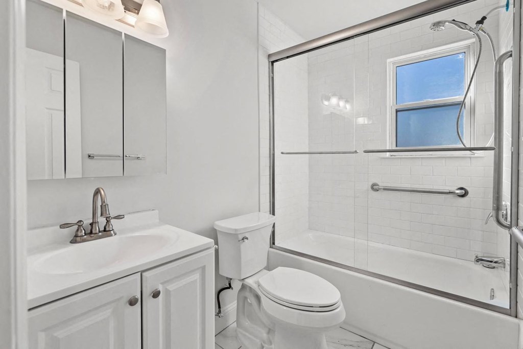 a white bathroom with a shower toilet and sink