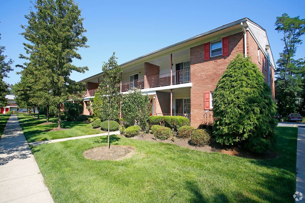 an apartment building with a lawn and trees
